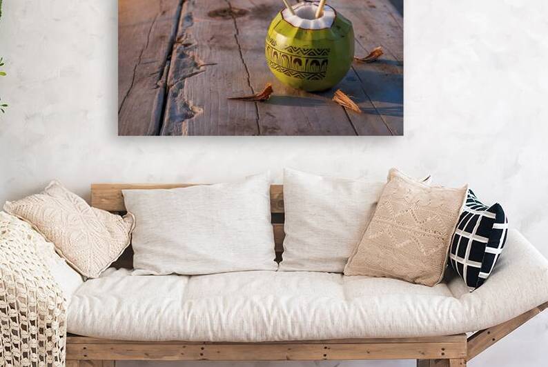 A coconut placed on a wooden surface with a straw by Romeu Hurmuzache