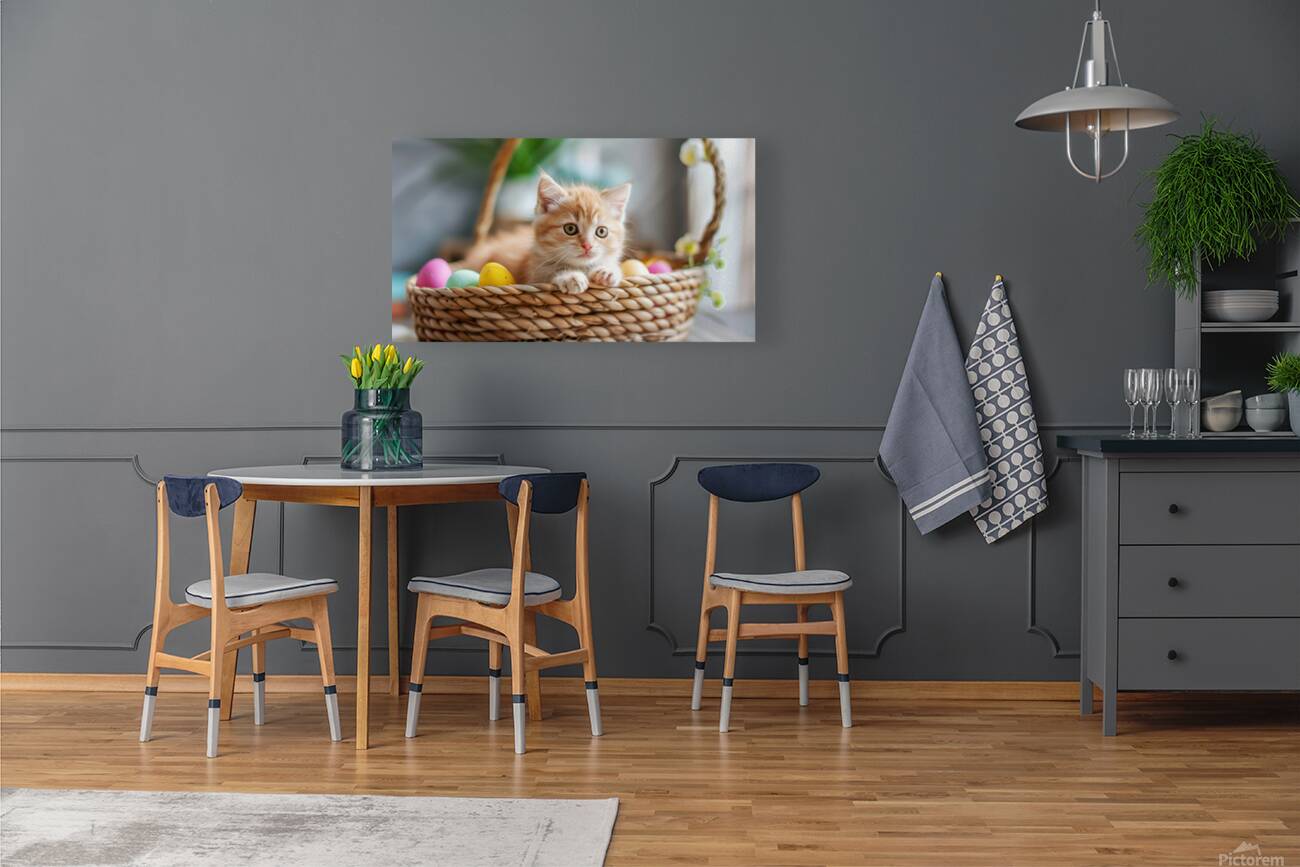 A cute kitten sits amidst Easter eggs in a basket. Reproduction