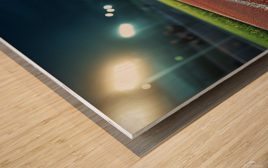 View of a well lit athletic track at night showcasing vibrant red surface and brightly illuminated surroundings Wood print