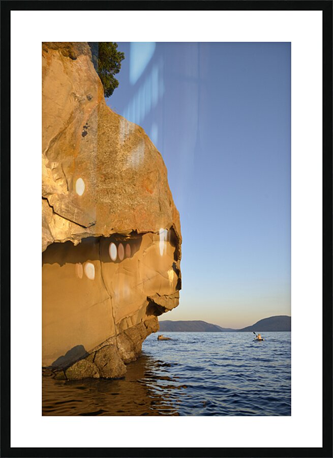 Sea kayaking under sculpted sandstone cliffs Picture Frame print