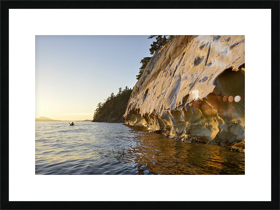 Sea kayaking under the sculpted sandstone cliffs Picture Frame print