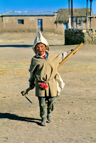 Indigenous boy with tools walks through a dusty village. Digital Download