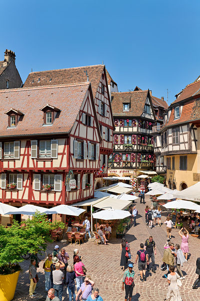 Visitors walk through Colmar on sunny day near timber framed hou Digital Download