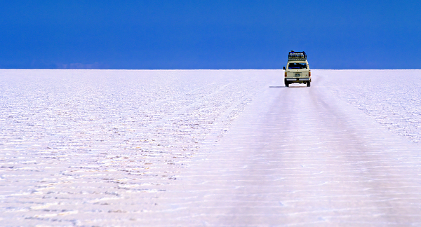 Van driving across vast white salt flat under blue sky. Digital Download