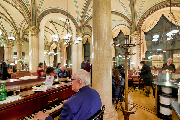 Man playing piano in an ornate bustling cafe. Digital Download