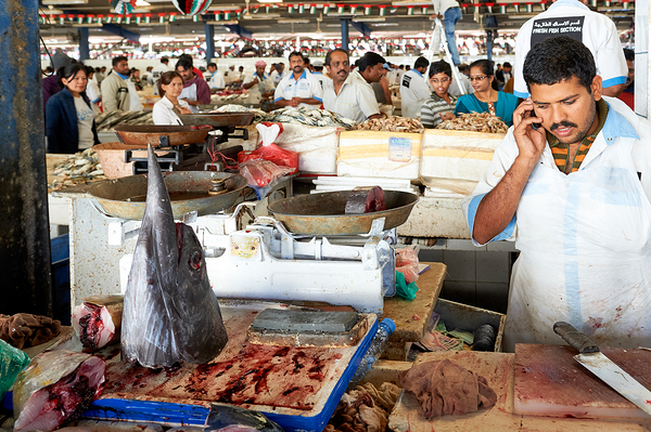 Man talks on phone at busy fish market in Dubai UAE Digital Download