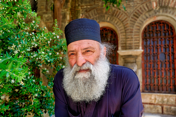 Elderly man with a beard poses near a historical building in a g Digital Download