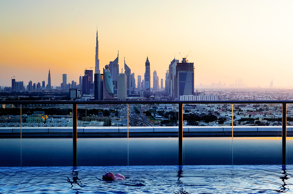 Swimming in infinity pool overlooking Dubai skyline at sunset Digital Download