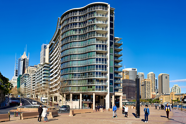 Modern curved building with balconies and city skyline. Digital Download