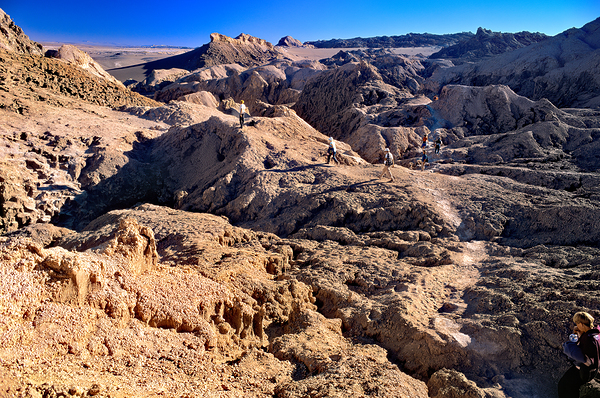 Hikers traverse a vast arid rocky desert landscape. Digital Download