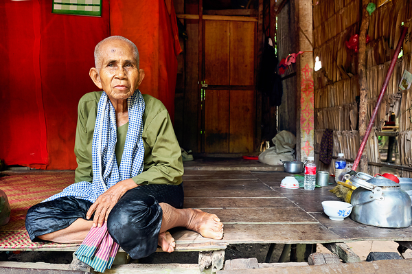 Elderly person sitting on floor in rustic dwelling. Digital Download