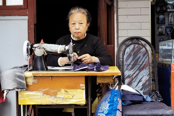 Elderly woman sews at machine in Shanghai China Digital Download