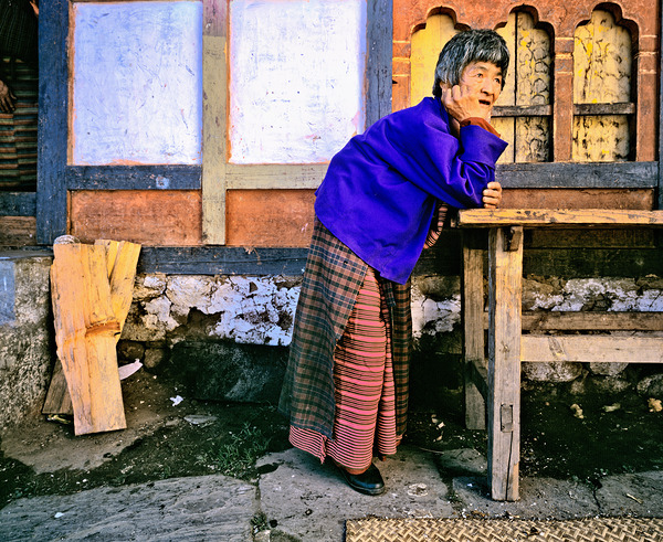 Smiling elderly woman in traditional dress leaning on wooden tab Digital Download