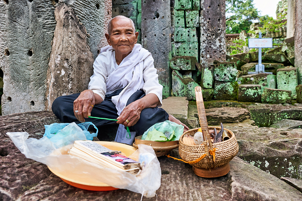 Elderly person selling goods at ancient temple ruins. Digital Download
