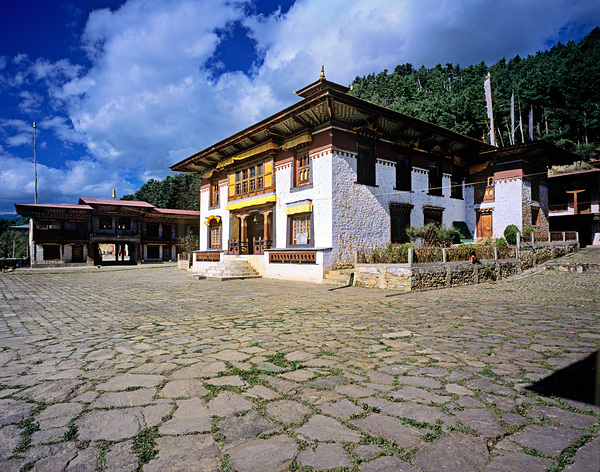 Traditional Bhutanese building with stone courtyard under a clou Digital Download