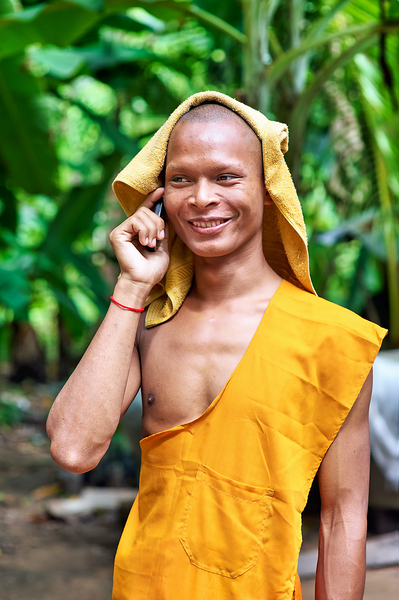 Smiling monk talks on phone with towel on head. Digital Download