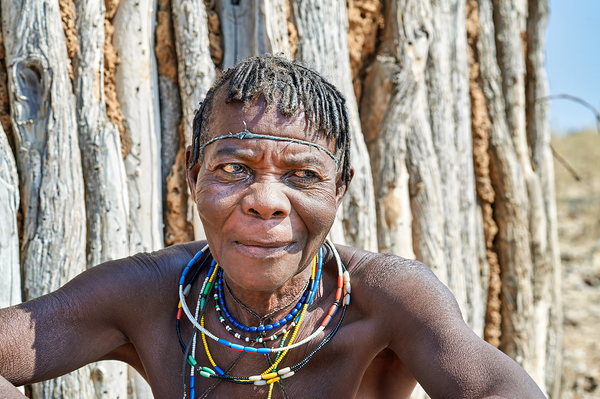 Old woman of Zemba Bantu ethnic group sits near wooden wall in N Digital Download