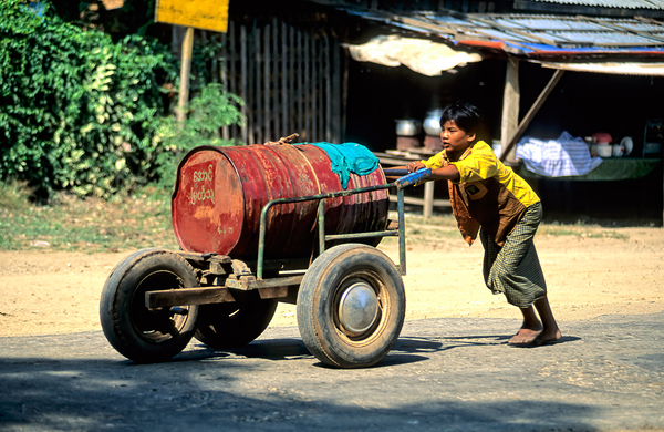 Boy pushes a cart down the street in Myanmar during the day Digital Download