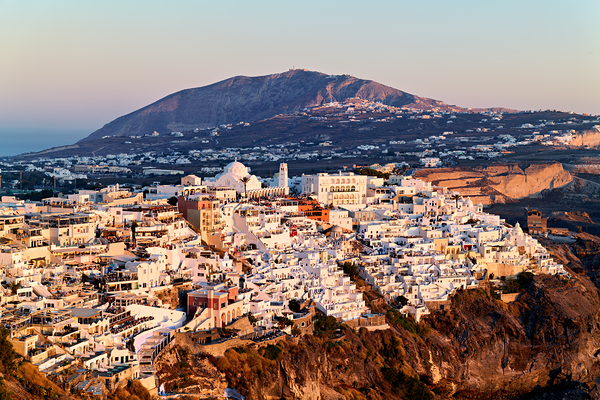 Santorini cliffside town at sunset with mountain backdrop. Digital Download