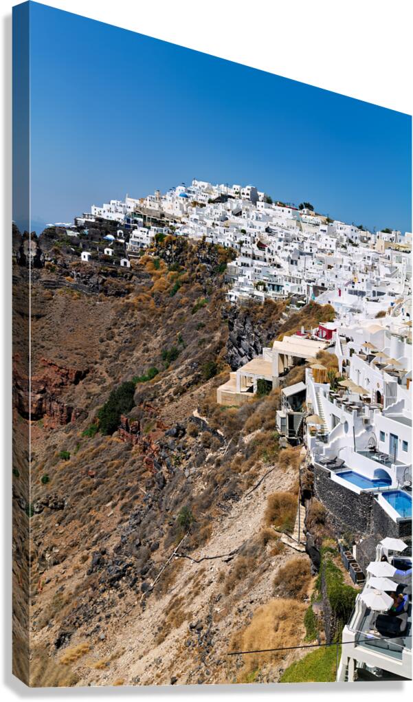Whitewashed buildings cascade down Santorinis volcanic cliffsid