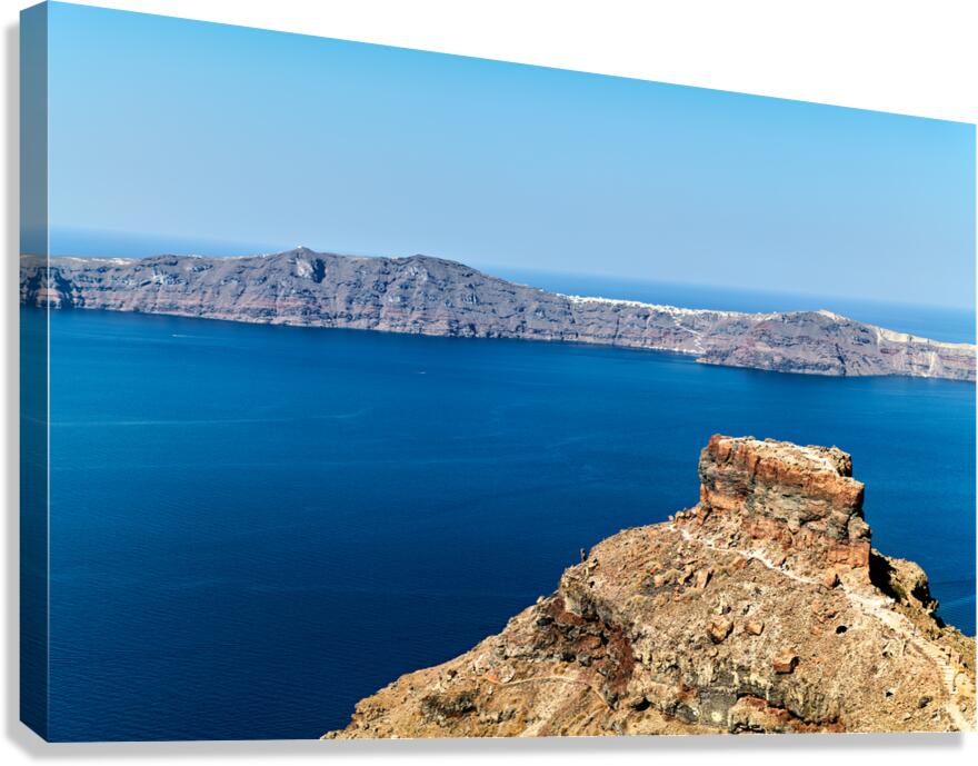 Santorinis volcanic caldera deep blue sea and distant island.