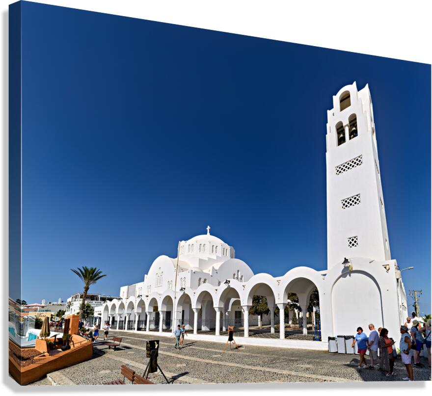 Iconic white church in Santorini under a bright blue sky.