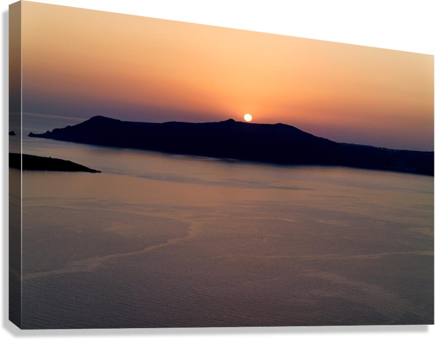Golden sunset behind dark island calm ocean.