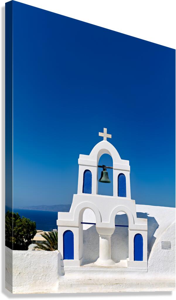 White bell tower against blue sky and sea.