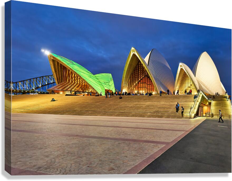 Sydney Opera House illuminated at dusk with people on steps.
