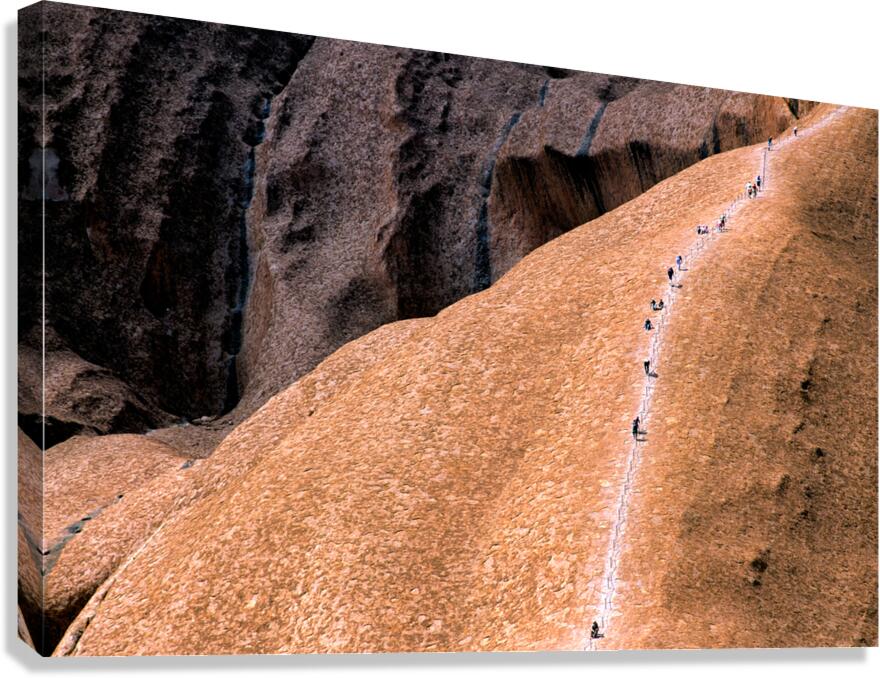 Hikers ascend Uluru using a chain ladder in Australia.