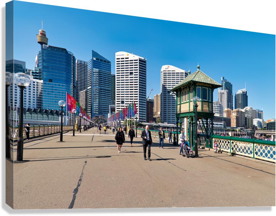 People walk on a sunny day with Sydney skyline.