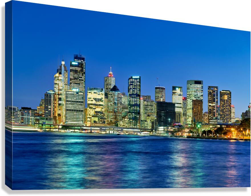 Sydney skyline at dusk with illuminated buildings and water.