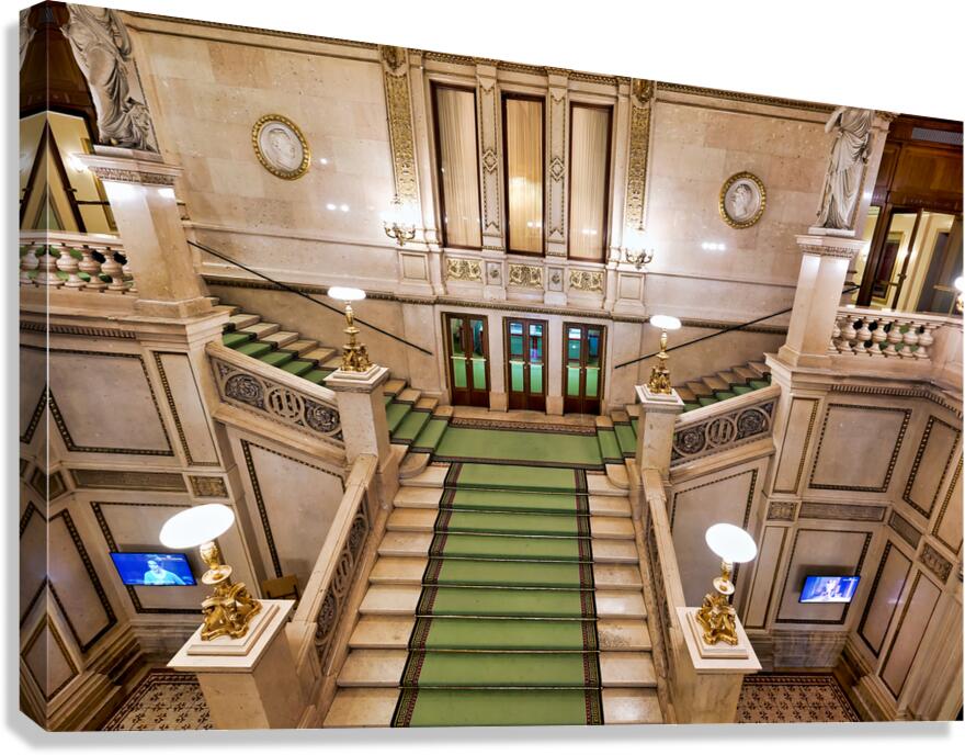 Ornate marble staircase with green carpet and classical statues.