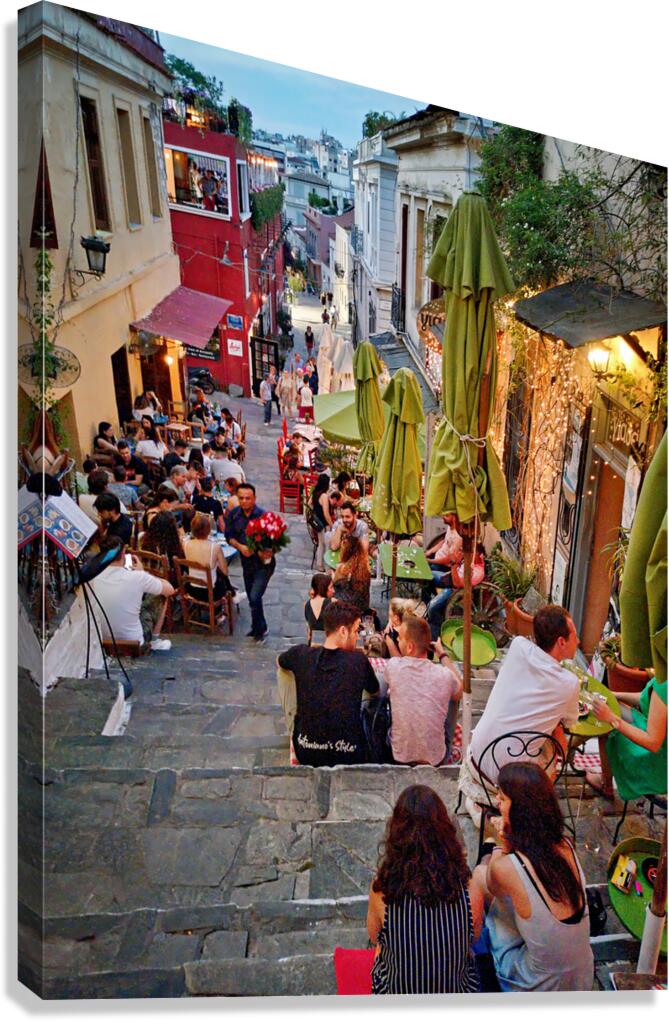 People enjoy drinks and food on a busy street in a city