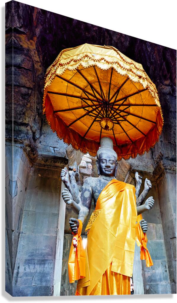 Ancient multi armed Vishnu statue with golden robe and umbrella.