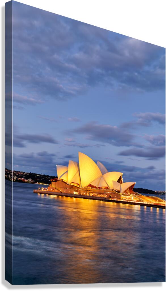 Sydney Opera House illuminated at dusk with harbor reflections.