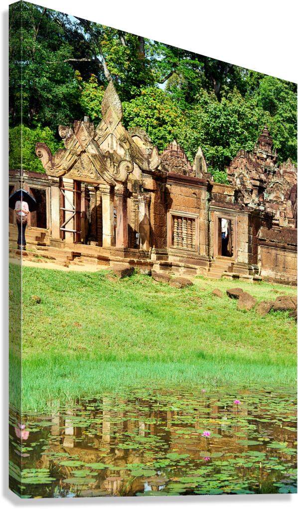 Ancient Cambodian temple reflected in a pond with water lilies.