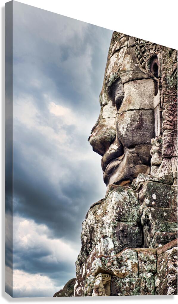 Ancient stone face carving against a dramatic cloudy sky.