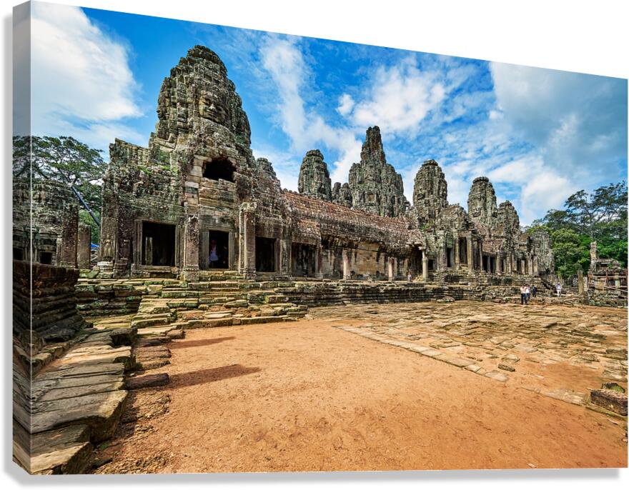 Ancient Bayon temple with stone faces under a blue sky.