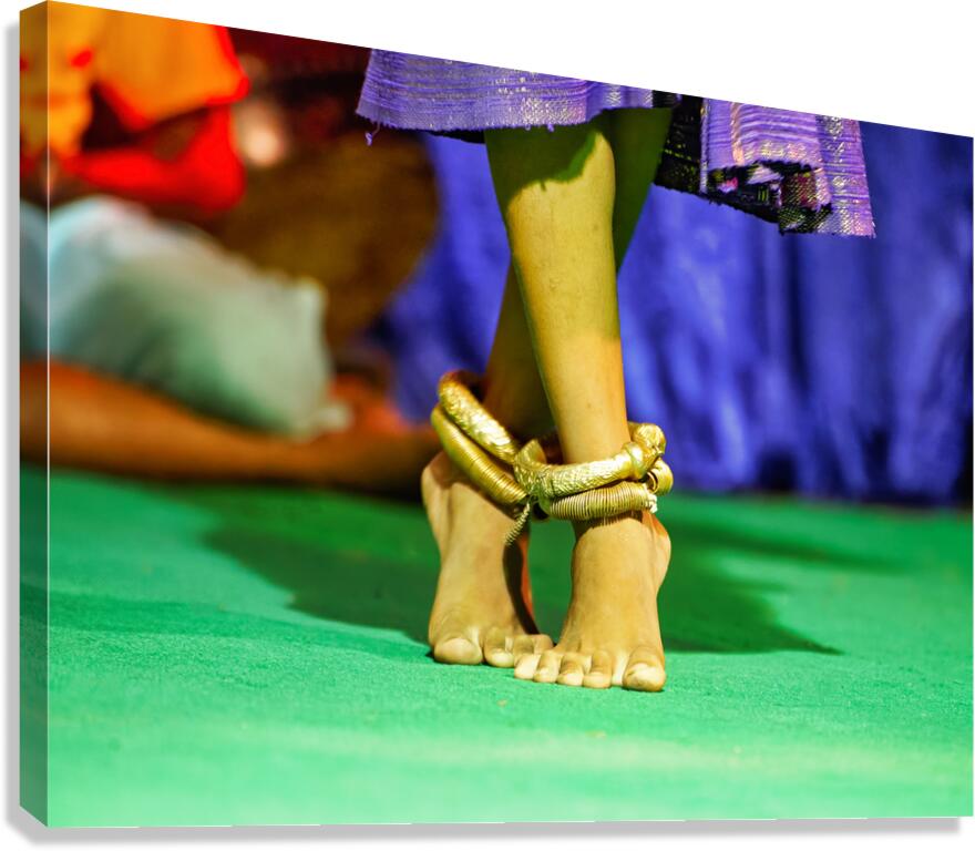 Bare feet with golden anklets on green surface.