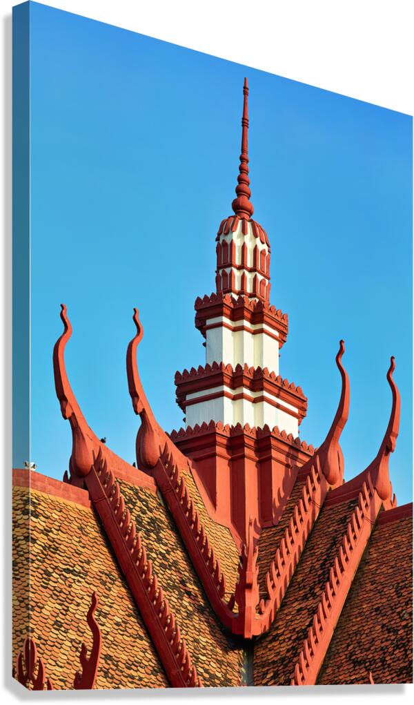Ornate red and white temple roof and spire against blue sky.