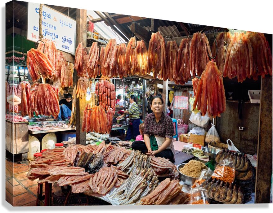 Woman sells dried fish at a bustling Cambodian market.