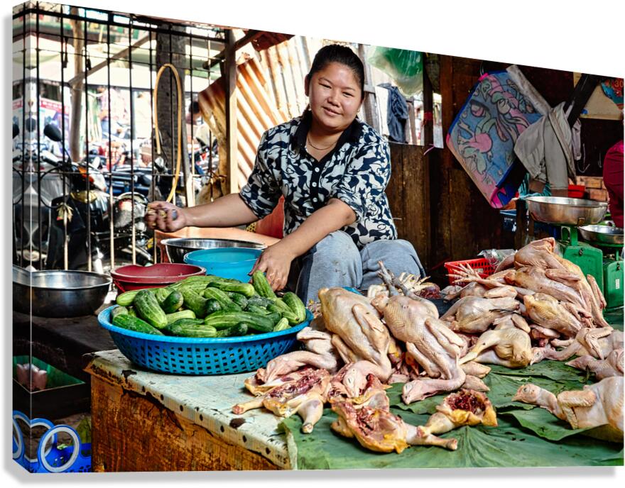 Woman sells raw chickens and cucumbers at a market.