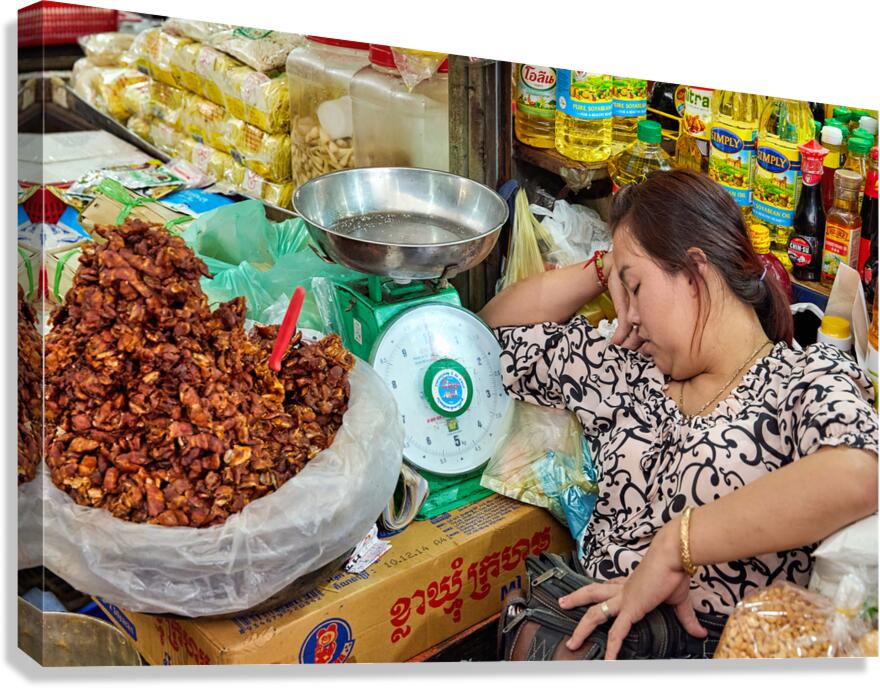 Woman sleeping at market stall amidst food and oils.