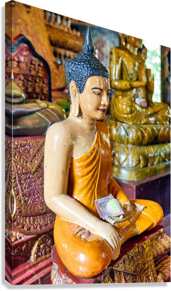 Seated Buddha statue with money and lotus offering.