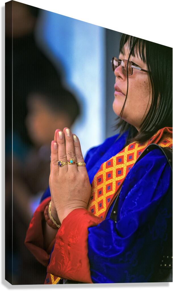 Woman in traditional dress with hands clasped in prayer.