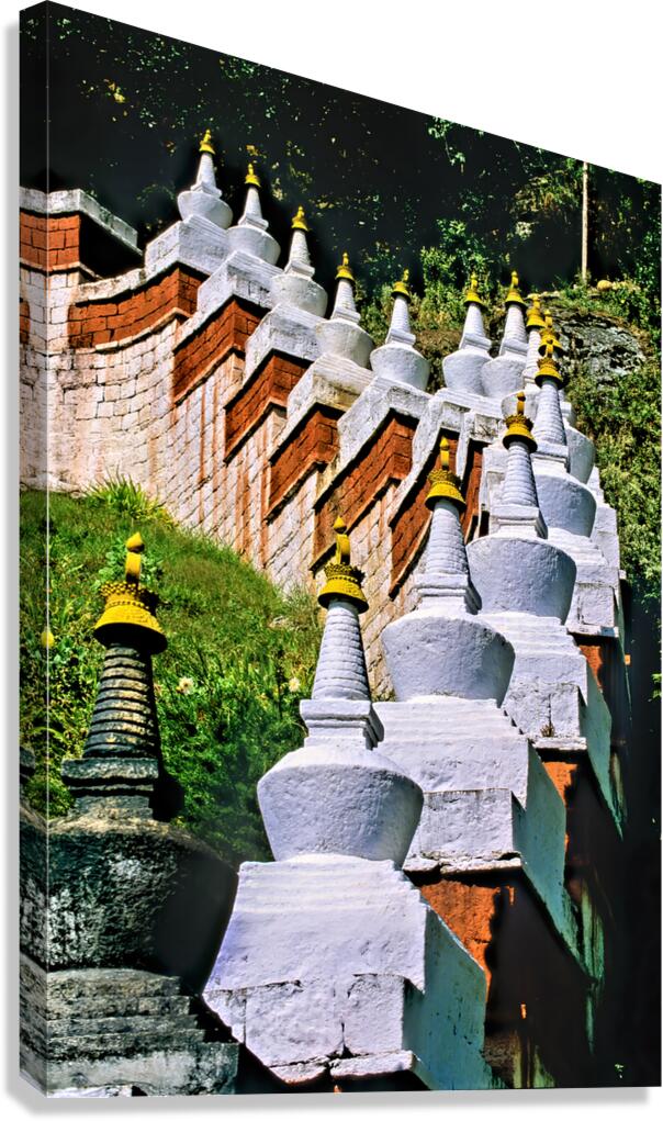White stupas with golden spires on a green hillside.