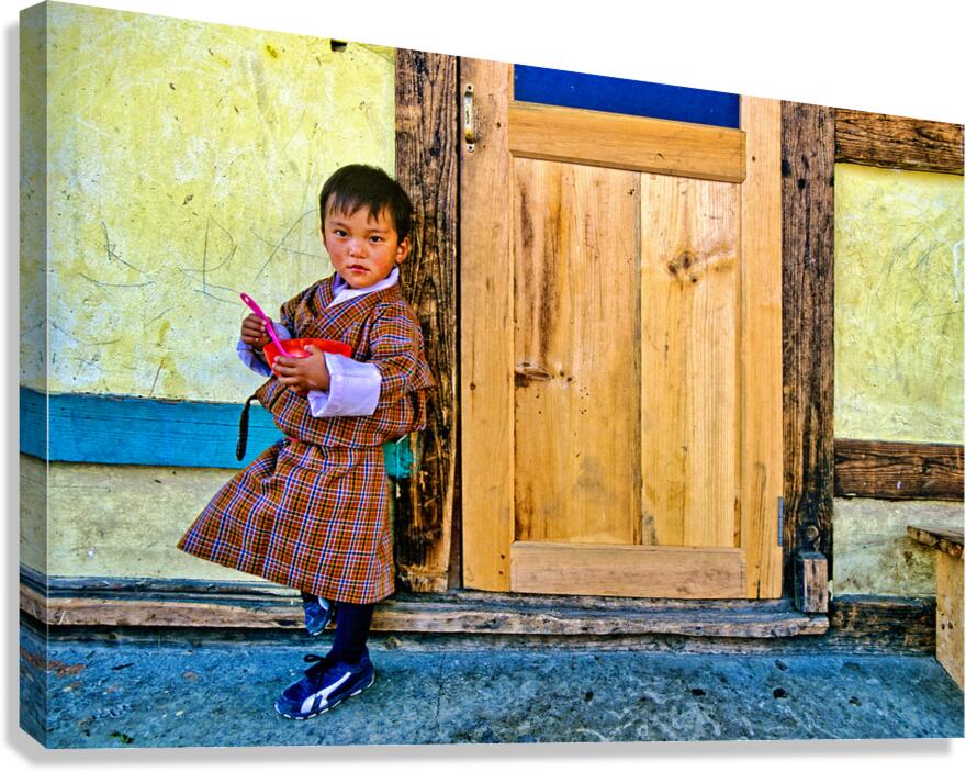 Bhutanese child in traditional dress holding a bowl and spoon.
