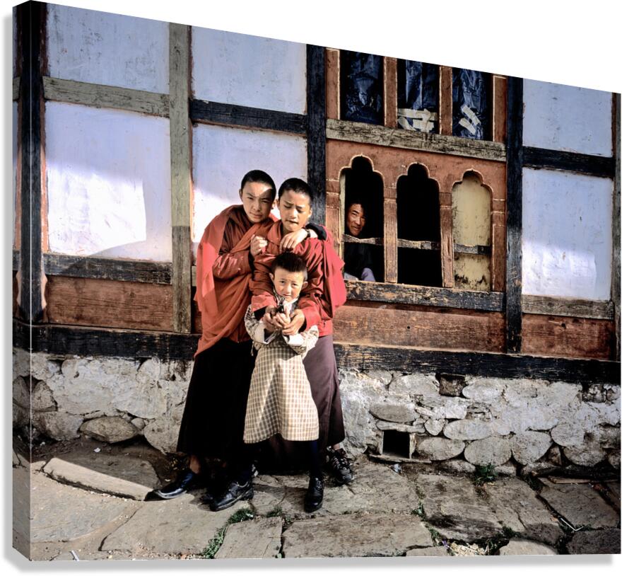 Children embracing one holding toy gun outside traditional bui