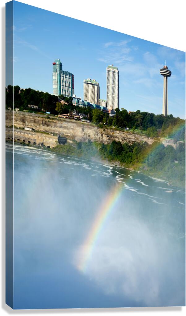 Rainbow over Niagara Falls with city skyline.